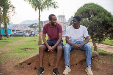 Two friends laugh as they look at each other in a public park in Africa