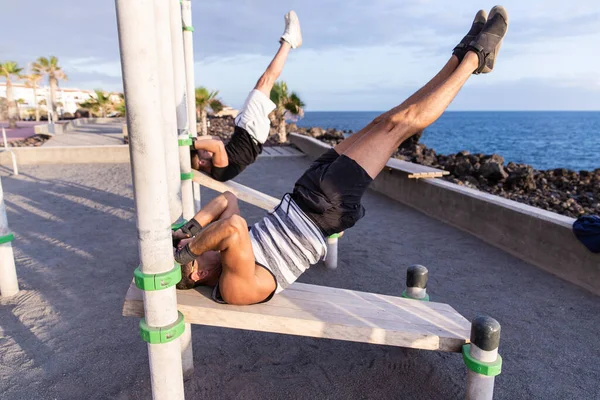 Calisthenics training in an outdoor gym, guys performing exercises on the bench