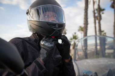 An African biker wears a helmet while sitting on his motorcycle, road safety