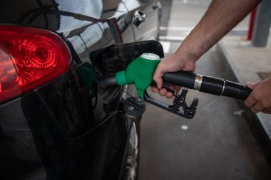 A man refuels his car, close-up on the hand holding the gas nozzle