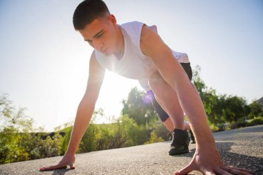 A runner in starting position during a workout, wellness and outdoor sport concept