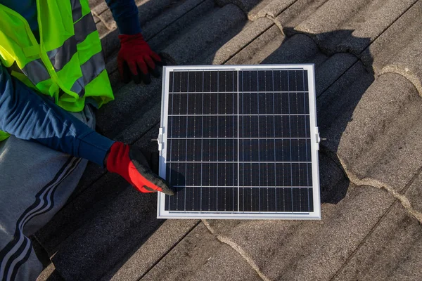 A technician installs a photovoltaic solar panel on a roof, sustainable energy.