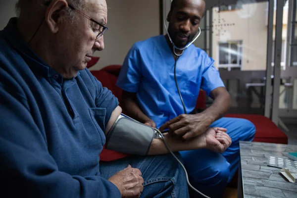 An elderly man during a home doctor checks his blood pressure