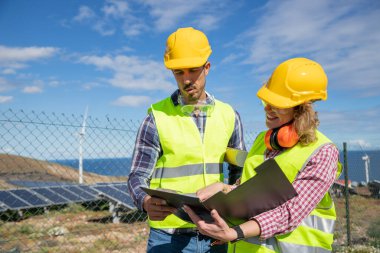 Two engineers at work analyze data in the solar farm, female and male coworkers.