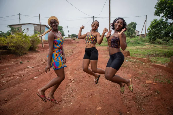 Three happy African girls jump and laugh, friendship and togetherness concept