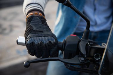 Motorsikletinin gidonunu tutan Afrikalı bir motorcunun yakın çekimi..