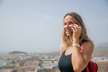 Beyaz bir kadın güneşli bir günde yürüyüş yaparken telefon eder..