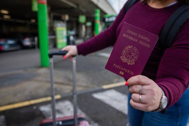 Pasaportunu otobüs durağında tutan İtalyan bir turistin yakın çekimi.