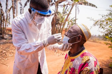 Afrikalı bir doktor yaşlı bir hastaya burun temizleme testi yapıyor..