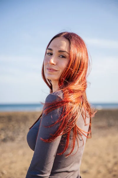 Vertical portrait of a young woman with a confident expression at the beach