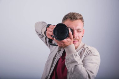 Bir fotoğrafçı DSLR 'ıyla fotoğraf çeker. Stüdyoda beyaz arka planda çekilir.