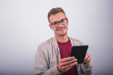 Gülümseyen genç bir adam tabletini kullanır.