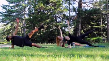 Bir beden eğitimi koçu, öğrencileriyle birlikte açık havada egzersiz yapar.