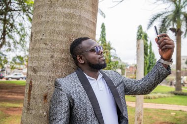 Afrikalı bir işadamı dışarıdayken akıllı telefonuyla bir video görüşmesi yapıyor.