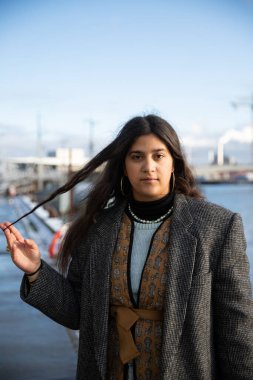 Kışın saçlarına dokunan kendinden emin bir Kuzey Afrikalı kızın dikey portresi.