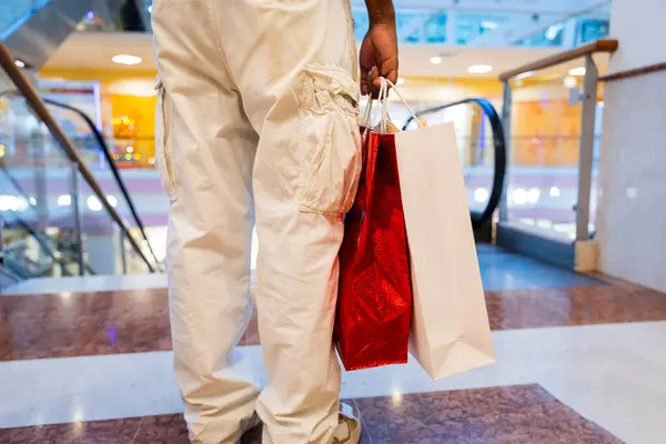 Close-up of shopping bags held in a man\'s hand in a shopping mall