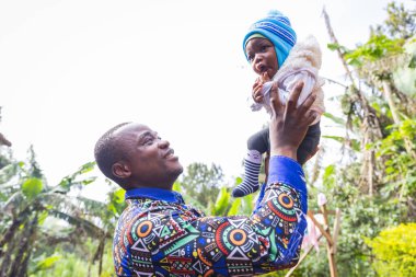 Afrikalı bir baba yeni doğmuş oğluyla oynar ve onu gökyüzüne kaldırır.