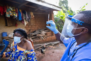 Genç bir doktor tarafından aşı olmak için sabırla bekleyen bir yaşlı..
