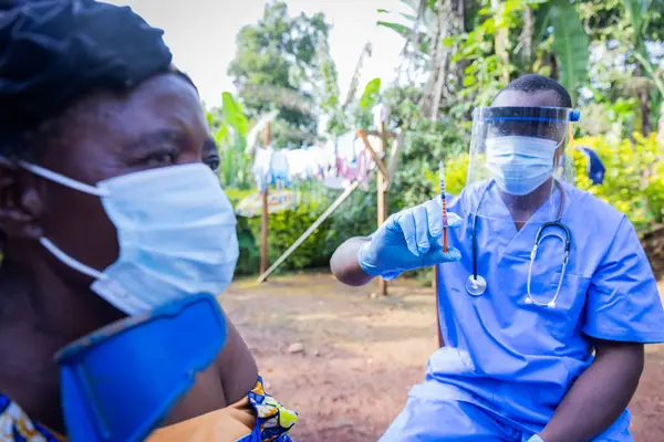 Yaşlı Afrikalı kadın omzunu açıyor ve bir doktordan iğne olmaya hazır..