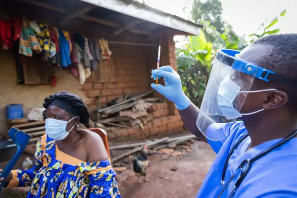 Genç bir doktor tarafından aşı olmak için sabırla bekleyen bir yaşlı..