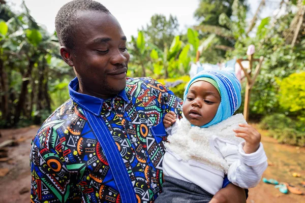 Gururlu genç Afrikalı baba kollarında oğluna şiddetle bakıyor..