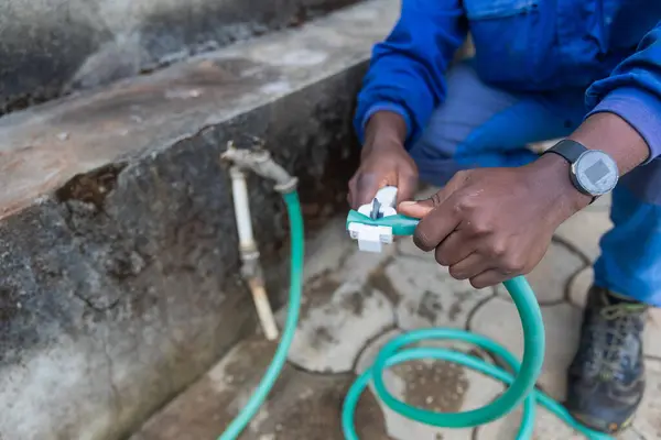 First shot of the hands of an African plumber cutting a pipe.