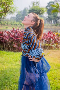 Gülümseyen kız Afrika elbisesi giyerken gökyüzüne bakıyor..