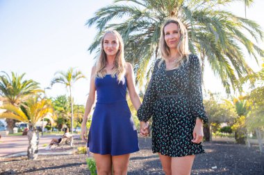 Anne ve kızı halka açık bir parkta yürürken el ele tutuşuyorlar..