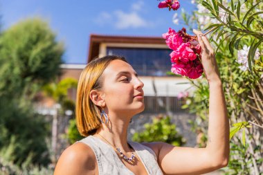 Bir kadın bahçede çiçek kokusu alıyor, bahar mevsimi, çiçek açan konsept.