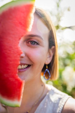 Bir kadın karpuz dilimini yüzüne doğru tutuyor, yaz havası.