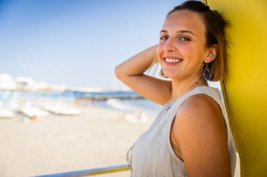 Bir kadın gülümsüyor ve bir plajda poz veriyor, fotokopi alanı olan bir fotoğraf..