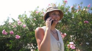 Bir kadın bahçede dururken cep telefonuyla konuşuyor.