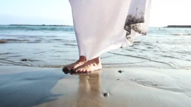 Dalgaların, kaygısızlığın ve yaz konseptinin etkisiyle denizde bir kızın ayaklarına yakın çekim