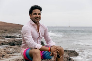 Sahilde kendine güvenen bir adam yaz tatilinde dinleniyor.