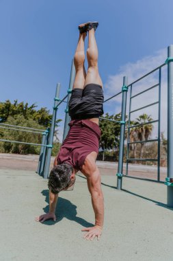 Bir adam dışarıda antrenman yaparken amuda kalkmış poz veriyor..