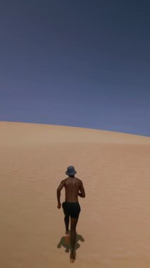Fuerteventura Kumullarında Mayo ve Balıkçı Şapkalı Atletik Siyah Adam 'ın İHA görüntüsü