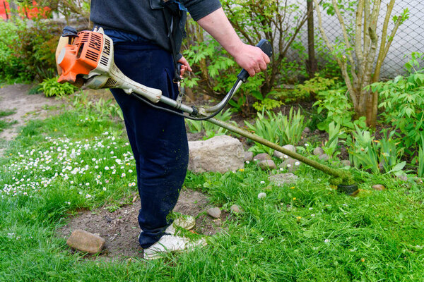 Grass mower working in the garden. Gardener cutting grass