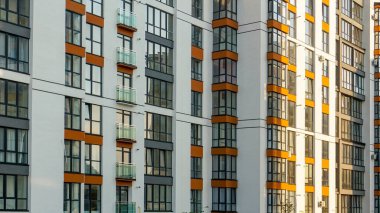 Çok katlı bir apartmanın ön cephesi. Pencereler ve balkonlar, çok katlı bir binanın duvarı. Şehrin çok katlı apartmanının yerleşim bölgesi..