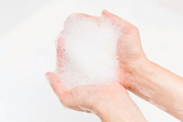 Female hand with soap foam close up view. Human skin care protection, washing hands. Shower milk cream shampoo.