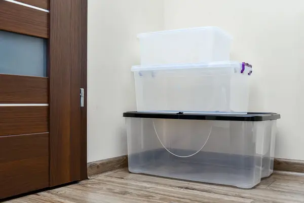 部屋の床に積み重ねられた空のプラスチック貯蔵箱 異なるサイズの蓋が付いている箱 移動項目のためのプラスチック透明な箱 ストック写真