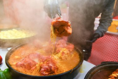 Lezzetli sokak yemekleri, et. Buharlı, sıcak yemek dışarıda hazırlandı. Satıcı bir parça kızarmış et gösteriyor, yemek tezgahı..