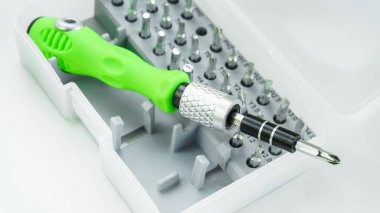 Plastik bir kutunun içindeki değiştirilebilir metal tornavida parçaları için değiştirilebilir manyetik nozüller. Beyaz arkaplanda izole edilmiş çalışma araçları.