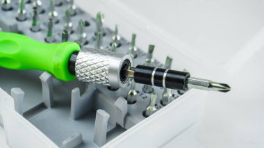 Plastik bir kutunun içindeki değiştirilebilir metal tornavida parçaları için değiştirilebilir manyetik nozüller. Beyaz arkaplanda izole edilmiş çalışma araçları.