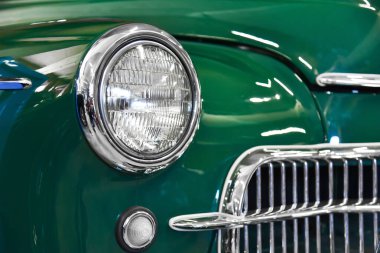 Round headlight on a green retro car. Fragment of car detail.  clipart