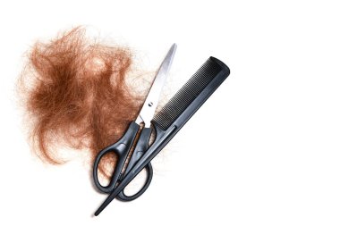Kuaför aletleri seti, makas ve tarak, beyaz bir arka planda, yeni kesilmiş kızıl-kahverengi saçların yanında. Saç şekillendirme, tımar ve saç kesimi..