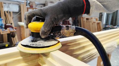 Zımparalama ahşap kaplama görüntüsü. Usta bir ahşap zımpara makinesinin eli siyah bir eldiven takıyor, öğütme makinesini tutuyor, ahşap yüzeyde çalışıyor..
