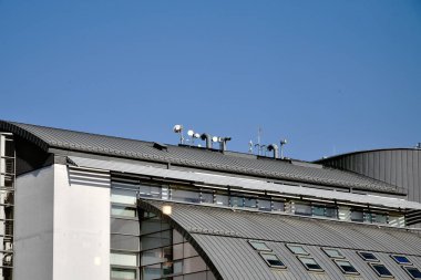 Binanın çatısı metal, havalandırma boruları, telefon ve cep telefonu iletişimi için antenler, internet ve manzandra pencereleri ve ofis binası ile kaplı.