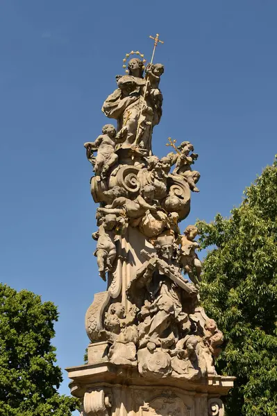 Barok dini anıtı. Heykel yapılmış azizler ve açık mavi gökyüzünün altındaki melekler. Hristiyan sembolleriyle süslenmiş tarihi taş heykel, kamusal alanda kutsal sanat ve kültür mirasını temsil ediyor..