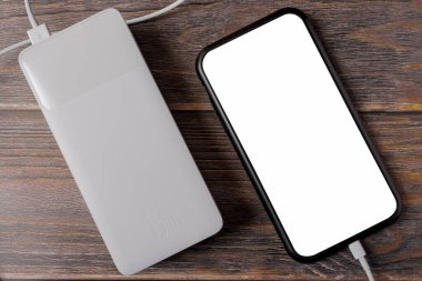 Taşınabilir şarj aleti ahşap arka planda akıllı telefonu şarj ediyor