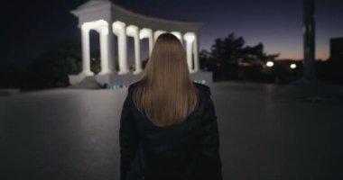 Akşam kentinde yürüyen kadın geri dönüyor.